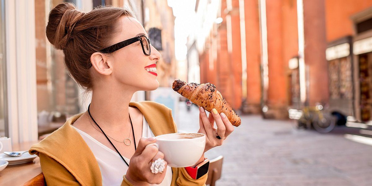 Femeie cu cafea și croissant